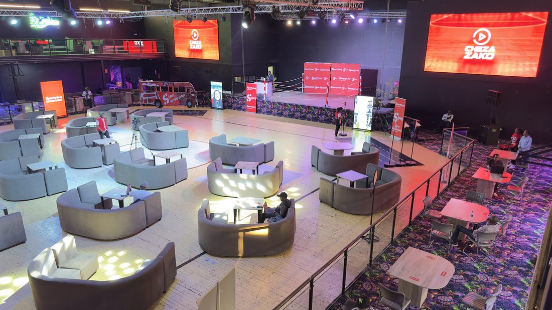 Lounge seating arranged in a darkened venue in front of lit red screens
